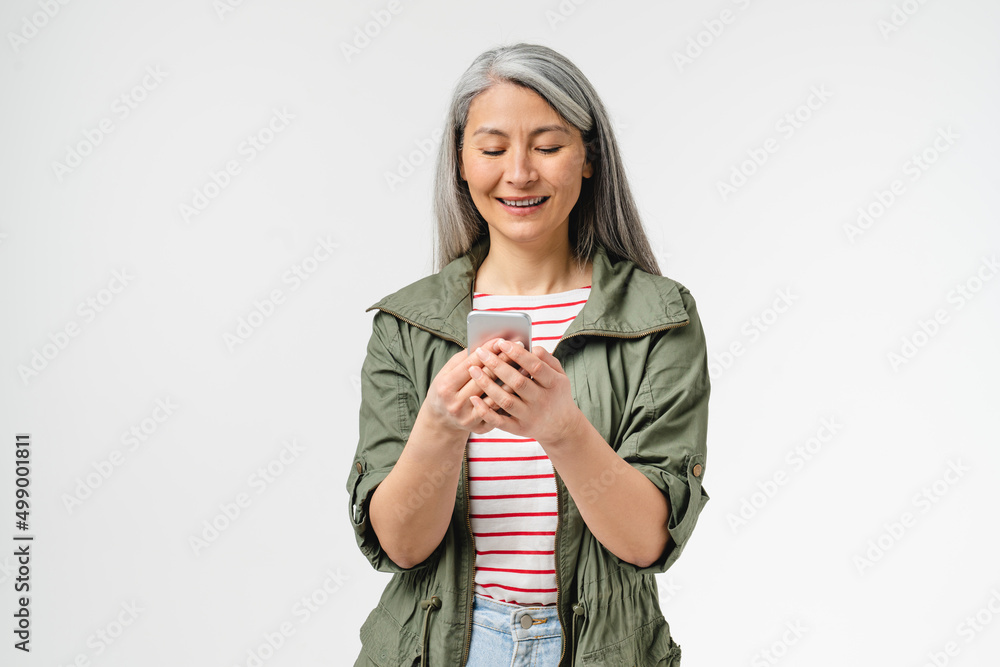 Smiling mature middle-aged woman mother grandmother using cellphone for mobile application, e-learning, e-banking online, social media surfing isolated in white background Smiling mature middle-aged woman mother grandmother using cellphone for mobile application, e-learning, e-banking online, social media surfing isolated in white background