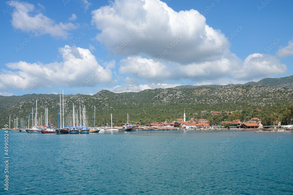 View of Uchagiz village and yachts at its shore on sunny day. Simena, Turkey.