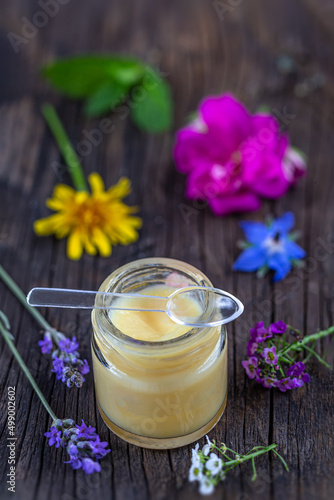 Canvas Print Jar of royal jelly (Food supplement) surrounded by medicinal flowers