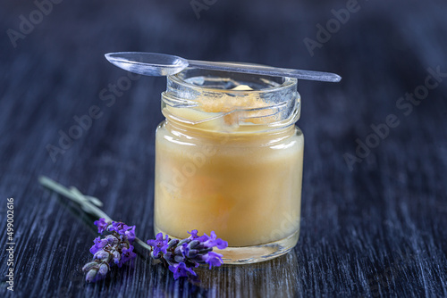 Canvas Print Close up of a jar of royal jelly covered with a spoon with sprigs