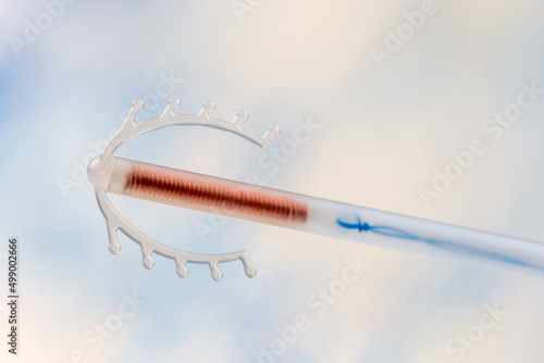 Close up of a copper IUD stored in a plastic tube isolated on a sky.