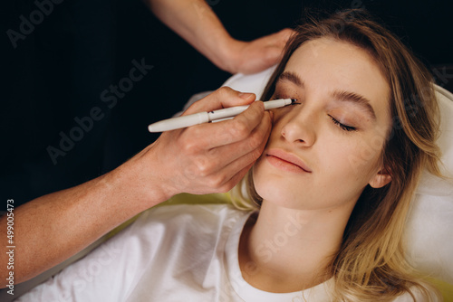 Blepharoplasty markup close-up on the face before the plastic surgery operation for modifying the eye region of the face in medical clinic. 2 doctors do plastic cosmetic operation