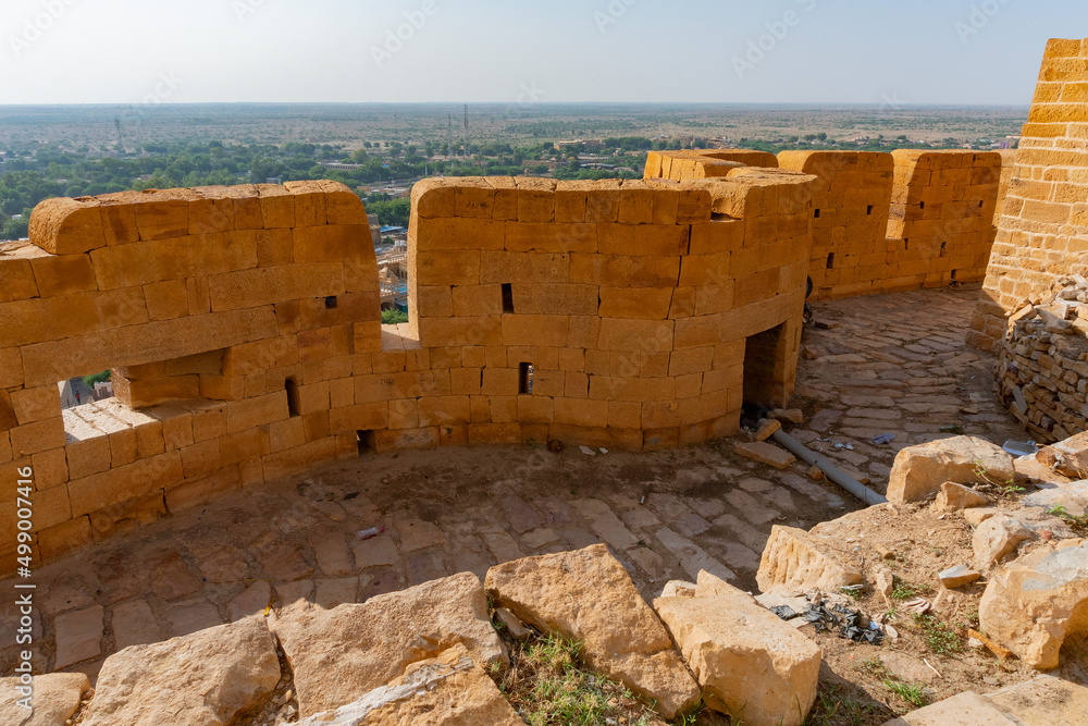 Jaisalmer, Rajasthan, India - October 13,2019 : Great walls of Jaisalmer Fort or Golden Fort, made of yellow sandstone, in the morning light with part of city in the frame. UNESCO world heritage site.