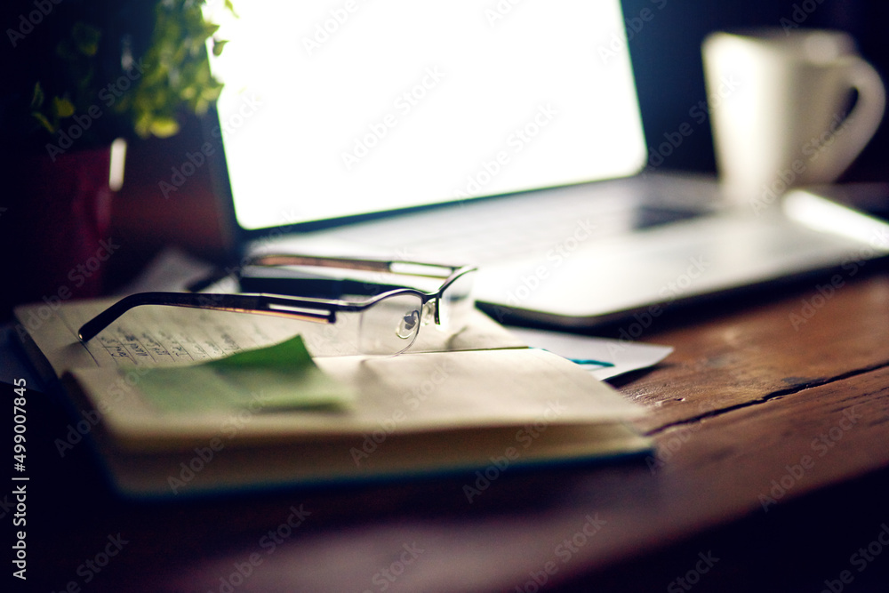 © K Seisa/peopleimages.com - Coming back to it in the morning. Shot of reading glasses on top of a notepad and a laptop on a desk.