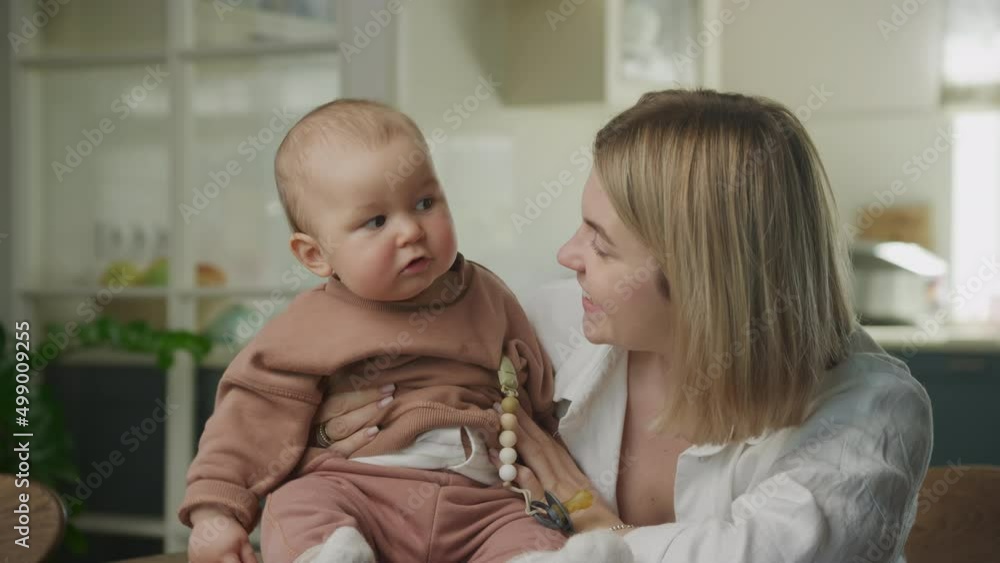 Young adult caucasian mother showing her son to look while talking in joy Young adult caucasian mother showing her son to look while talking in joy