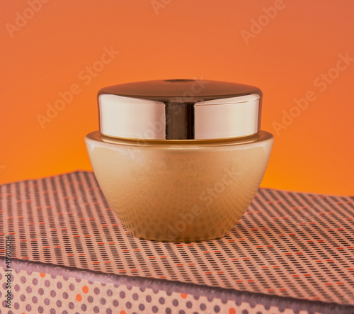 Cosmetic,cream tub isolated on a cool orange gradient background. photo