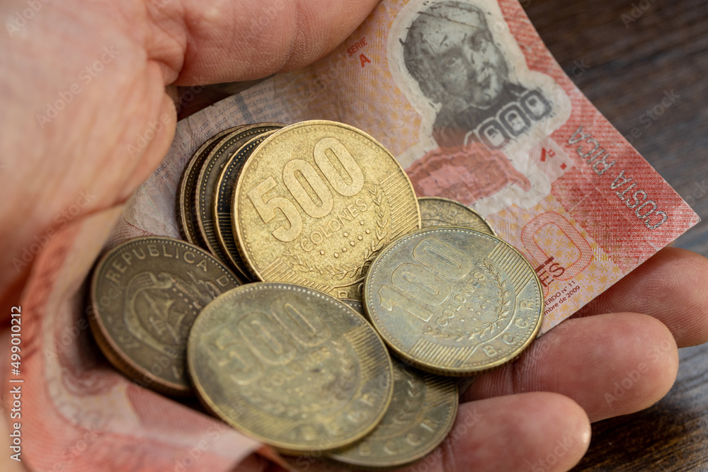 Costa Rica money, a handful of shiny Coins and a thousand Colon banknote held in your hand Costa Rica money, a handful of shiny Coins and a thousand Colon banknote held in your hand