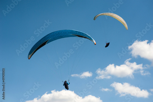 Two paragliders flying in the blue sky against the background of clouds. Paragliding in the sky on a sunny day.