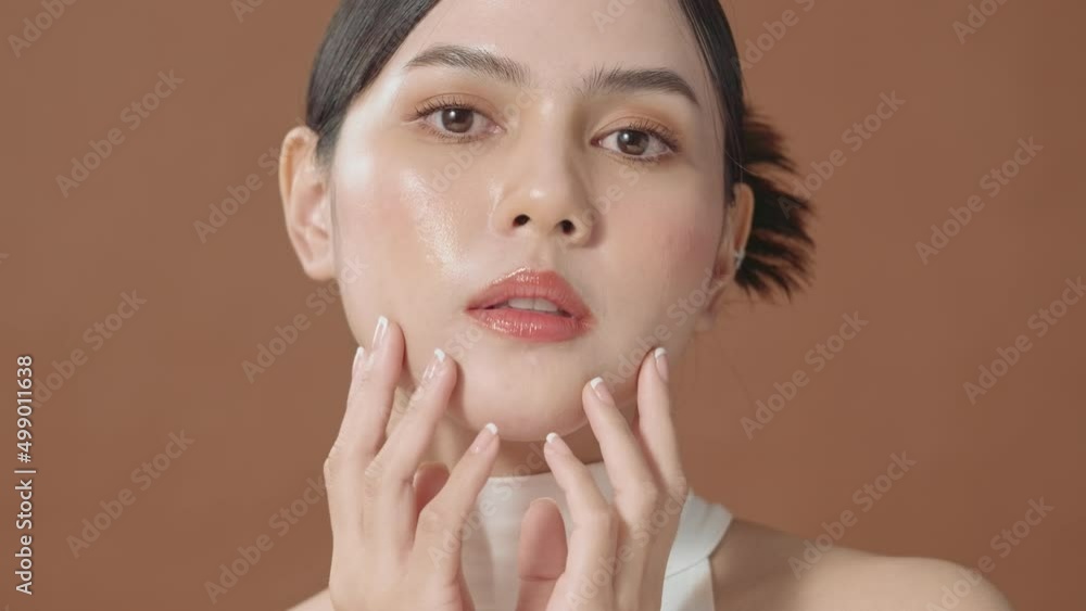 A young woman with beautiful face smiling , touching her face over brown background , beauty skin care concept A young woman with beautiful face smiling , touching her face over brown background , beauty skin care concept