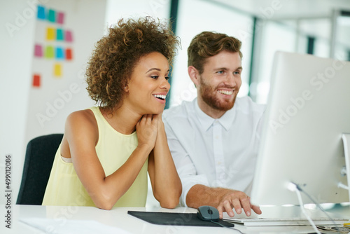 Aw, I love cat videos. Shot of a businesswoman and her male colleague looking at something on a computer screen together.