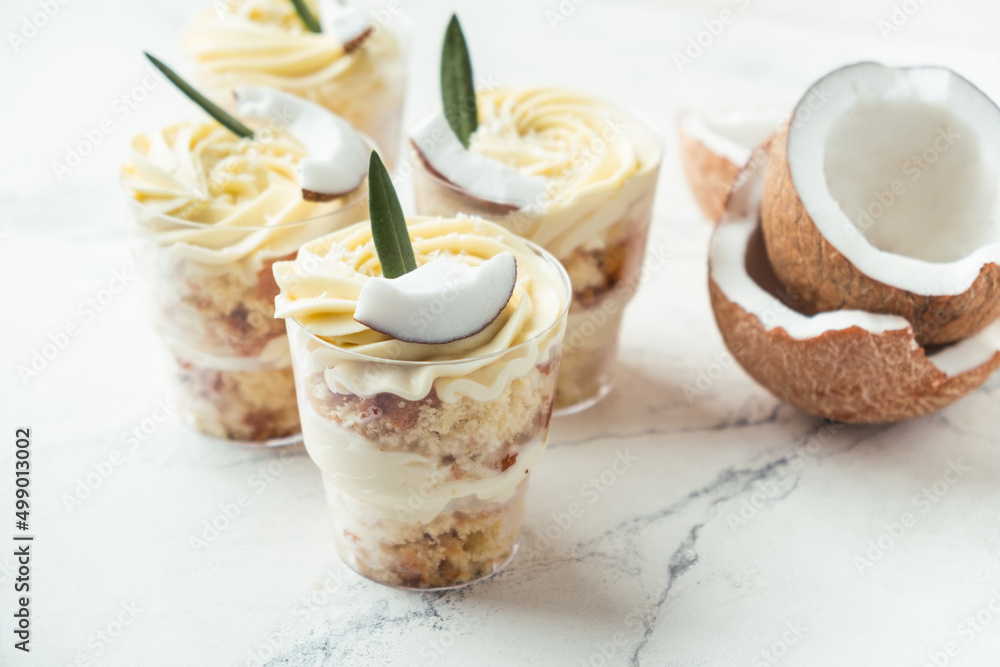 English layered dessert trifle of buscuit dough, custard and whipped cream with fresh coconut pieces on the white background English layered dessert trifle of buscuit dough, custard and whipped cream with fresh coconut pieces on the white background