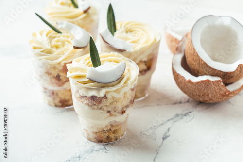 English layered dessert trifle of buscuit dough, custard and whipped cream with fresh coconut pieces on the white background photo