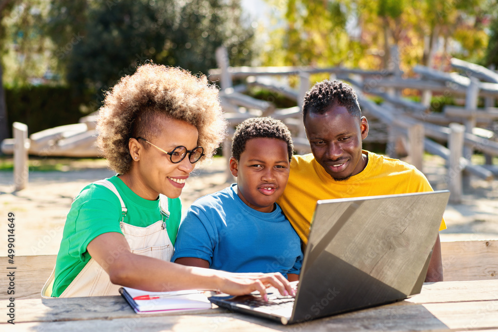 Beautiful young Afro American parents and cute little son are using a laptop Beautiful young Afro American parents and cute little son are using a laptop