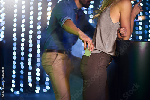 Hide it or lose it. Cropped shot of a man stealing a womans phone from her pants pocket in a nightclub.