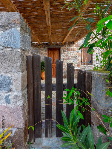 A natural wood external entrance door and low stonewall fence, Pachia Rahi village, Aegina island, Greece photo