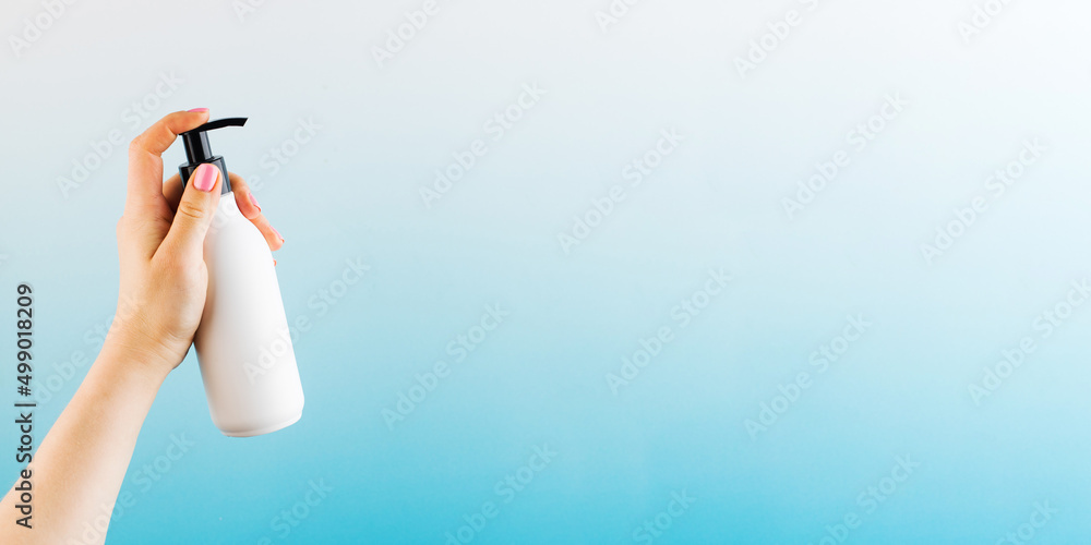 A mockup of a white dispenser with a cosmetic product in a woman's hand on a blue background. A mockup of a white dispenser with a cosmetic product in a woman's hand on a blue background.