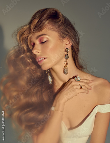Young attractive women model presenting your jewelry . Wearind white dress. Nude makeup, perfect skin, long hair. White background.