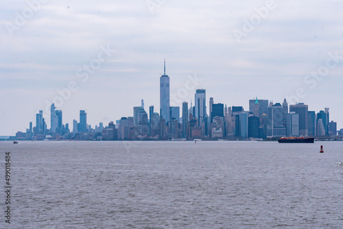 A tugboat pushing a barge in New York Harbor with the Manhattan Skyline in the background.   New York City  New York  USA