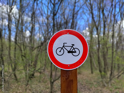 Road sign prohibiting bicycles entering the blurred forest in the background.
