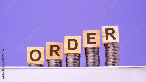 wooden cubes with the word Order on money pile of coins, business concept