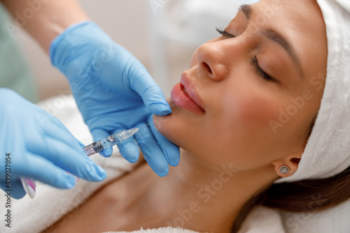 Closeup of young woman receiving hyaluronic acid injection in beauty salon. Cosmetology photo