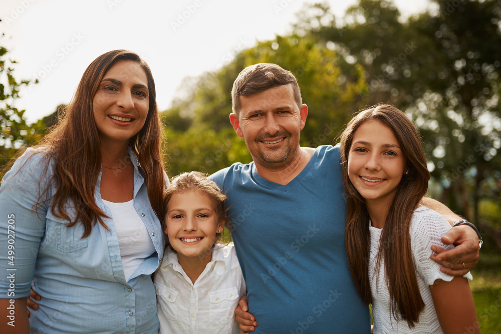 This is what family looks like. Cropped portrait of a young family of four standing outside. This is what family looks like. Cropped portrait of a young family of four standing outside.