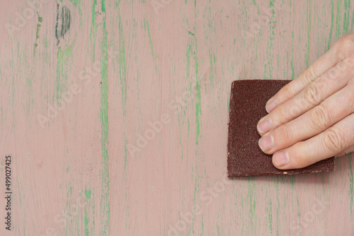 La mano lijando madera con papel de lija photo