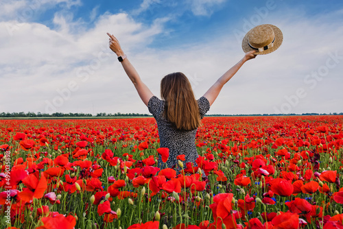 Woman in a beautiful field of red poppy flowers