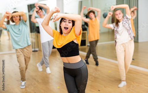 Group of positive teenagers dancing modern dance in ballroom.