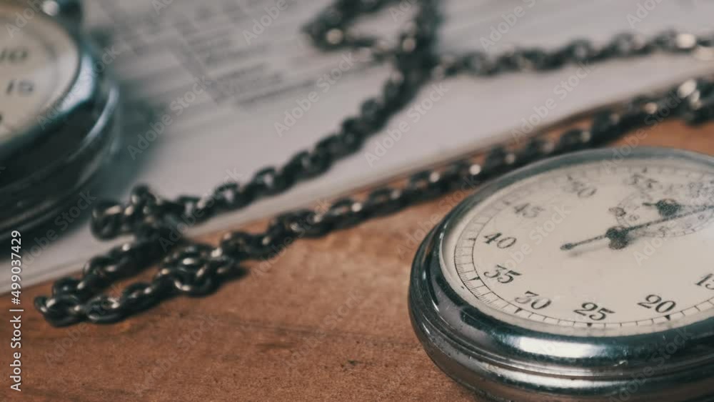 An antique stopwatch lies on wooden writing desk with retro documents