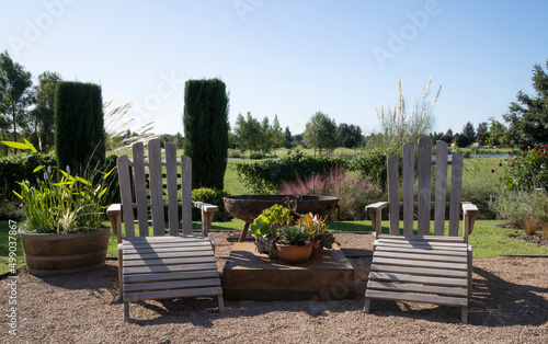 View of the garden in a sunny day. Beautiful plant arrangement and teak furniture. 