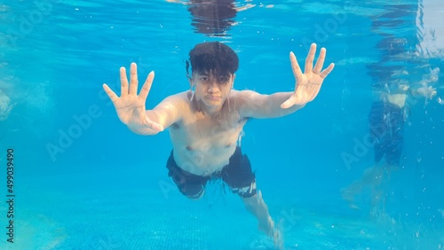 teenage boy swimming underwater in the pool, active teenager who likes to dive and have fun under water, kids fitness and sports
