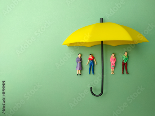 The yellow umbrella protected a small woman against a green background. The concept of self -protection insurance.