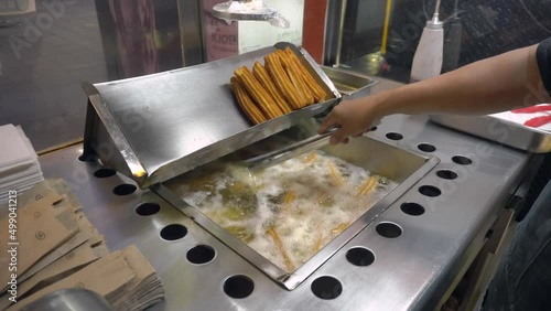 Frying Churros in deep oil in Churreria. Traditional Mexican Dough Pastry Snack photo