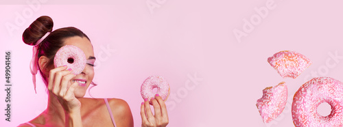 banner happy young girl putting donut over her eyes in pink