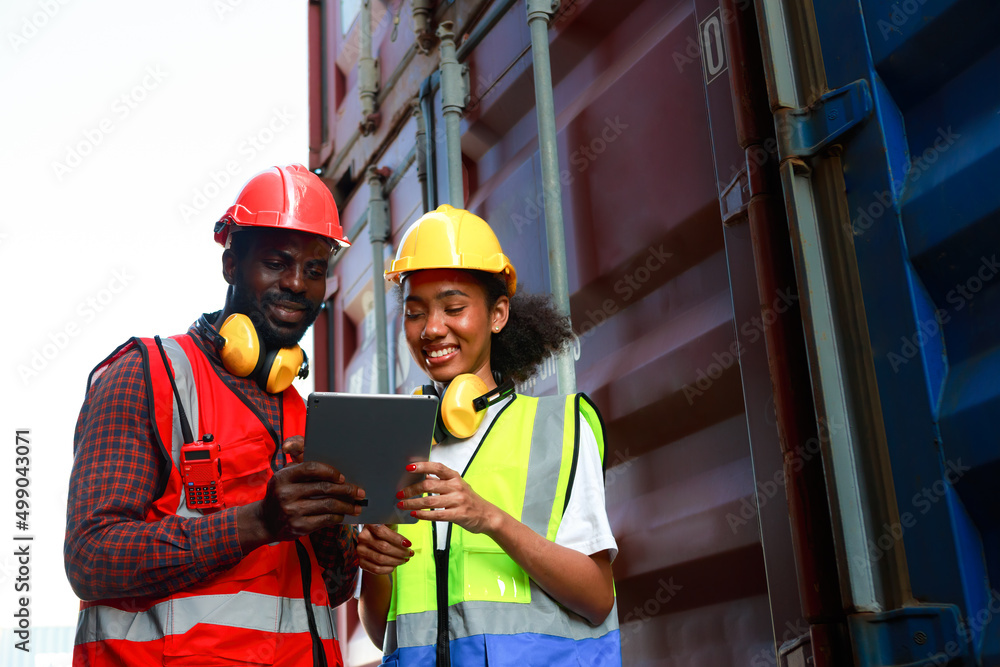 A female engineer and a young African-American man monitor and supervises the loading of containers at a commercial shipping port. A female engineer and a young African-American man monitor and supervises the loading of containers at a commercial shipping port.