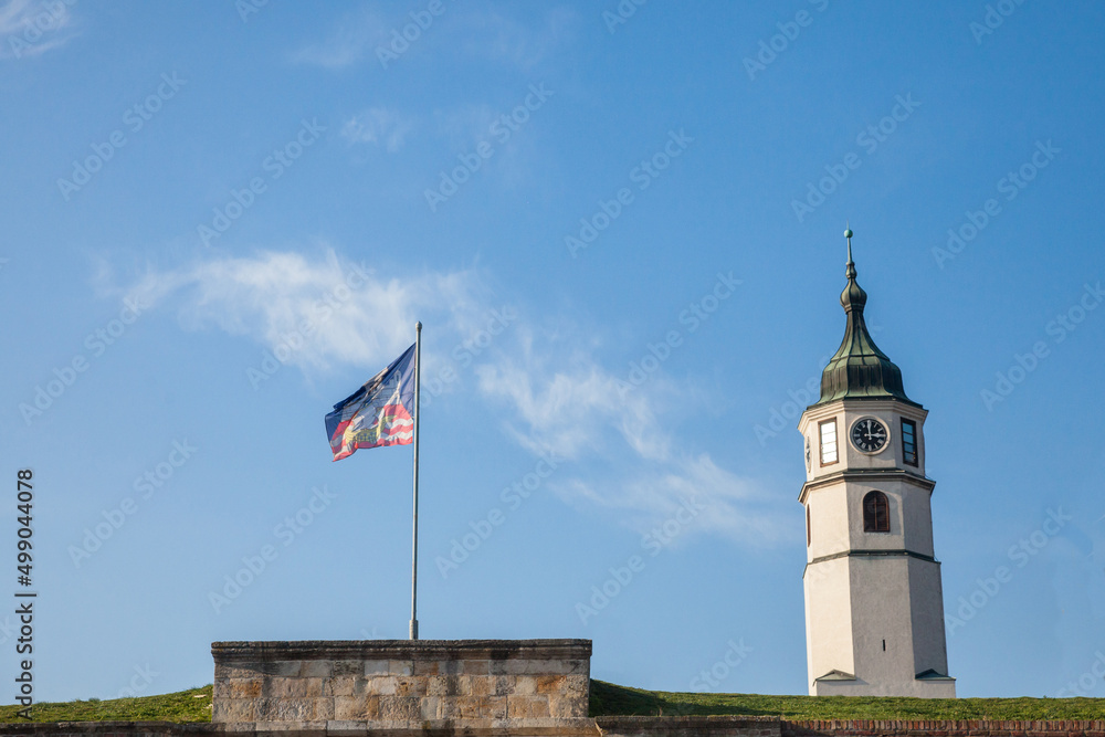 Flag with the coat of arms of belgrade next to Clock tower of Kalemegdan, also known as Sahat Kula, during a sunny afternoon. Kalemegdan is a fortress, the main landmark of Belgrade, Serbia...
