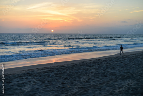Santa Monica, California, USA - April 10, 2022: A man is walking along Santa Monica Beach during the sunset