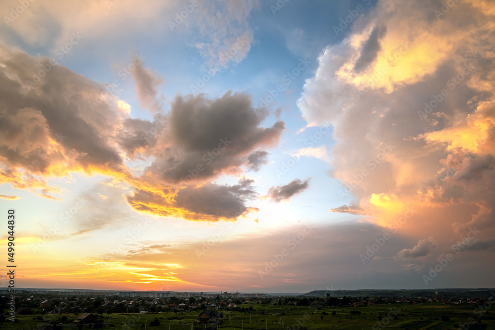 Dramatic sunset rural landscape with puffy clouds lit by orange setting sun and blue sky. Dramatic sunset rural landscape with puffy clouds lit by orange setting sun and blue sky.