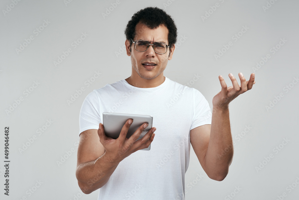 I got disconnected, just like that. Shot of a man using a digital tablet while standing against a grey background. I got disconnected, just like that. Shot of a man using a digital tablet while standing against a grey background.