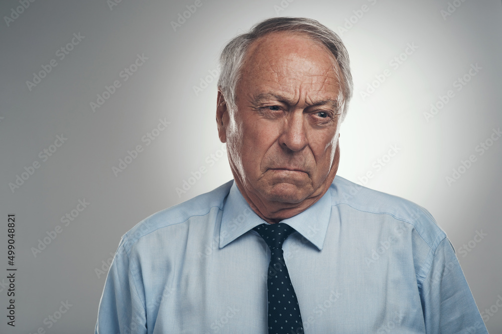 Psht, I dont really care. Shot of a senior businessman standing alone against a grey background in the studio and looking annoyed. Psht, I dont really care. Shot of a senior businessman standing alone against a grey background in the studio and looking annoyed.