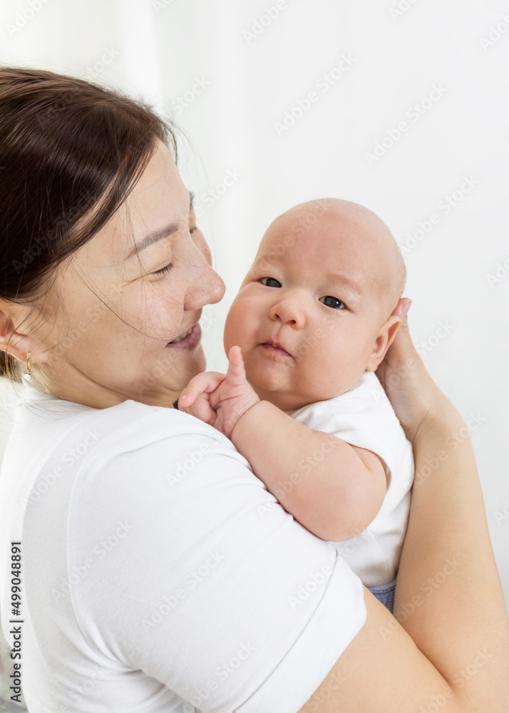 baby and mother at home. maternal hugs. motherhood. asian mother holds baby in her arms and smiles.selective focus baby and mother at home. maternal hugs. motherhood. asian mother holds baby in her arms and smiles.selective focus