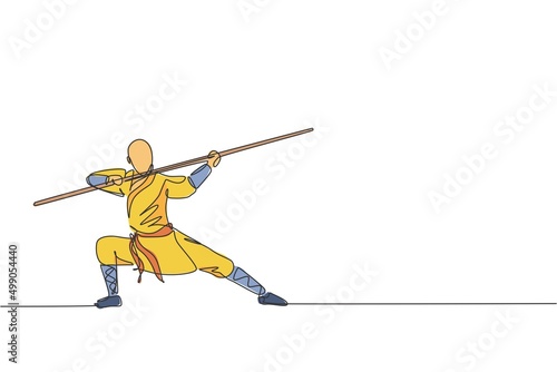 One single line drawing of young energetic shaolin monk man exercise kung fu fighting with stick at temple vector illustration. Ancient Chinese martial art sport concept. Continuous line draw design photo