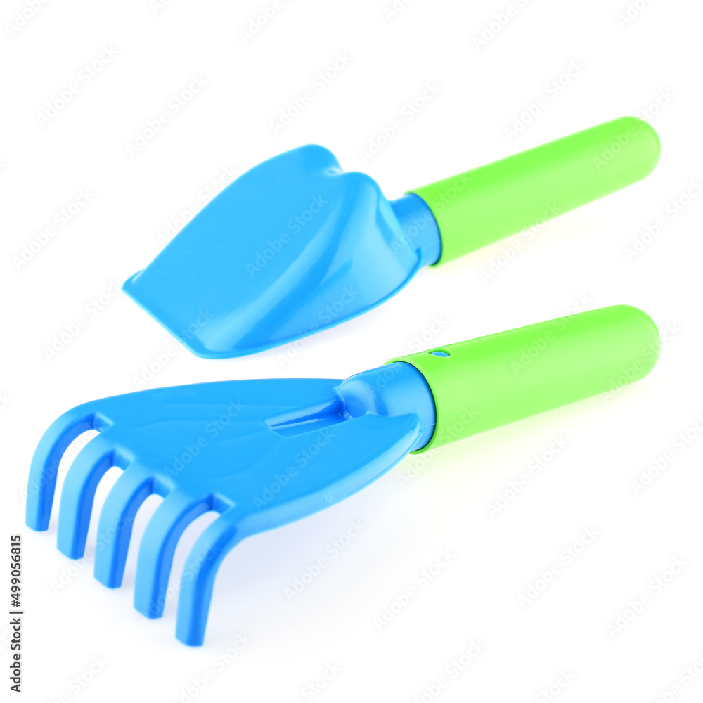 A set of children's toys for playing in the sandbox. Colored rake and shovel made of plastic, isolated on a white background, close-up. Early child development, children's leisure concept A set of children's toys for playing in the sandbox. Colored rake and shovel made of plastic, isolated on a white background, close-up. Early child development, children's leisure concept