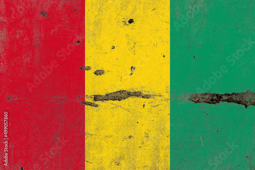 Guinea flag on a damaged old concrete wall surface