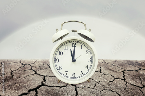 Alarm clock on barren ground, Global warming time.