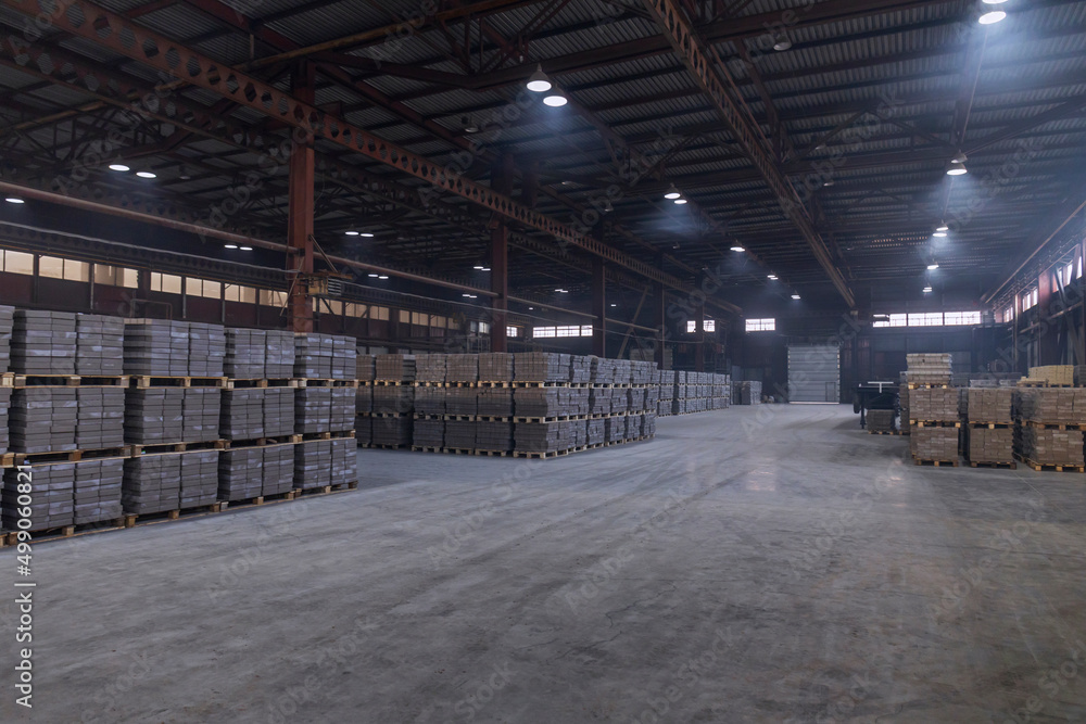 Warehouse of finished products at the enterprise for the production of bricks for construction. Industrial workshop with concrete floor and artificial lighting. 