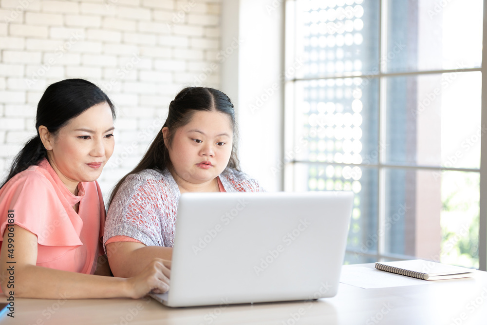down syndrome teenage girl and her teacher using laptop computer together on a table down syndrome teenage girl and her teacher using laptop computer together on a table