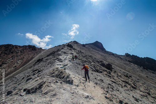 horizontal shot of mountaineers walking towards the summit of a rocky mountain on a sunny day in the Nevado de Toluca in Mexico