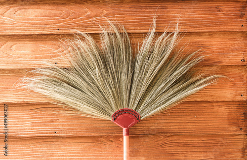 Grass broom leaning against the wall